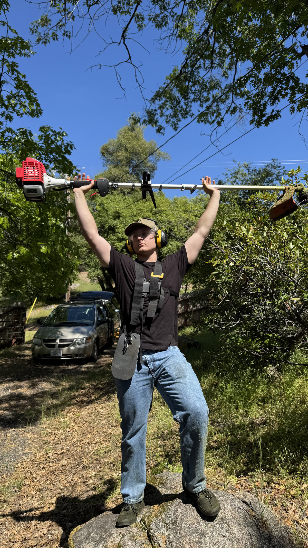 Crew member holding weed eater overhead in victory pose