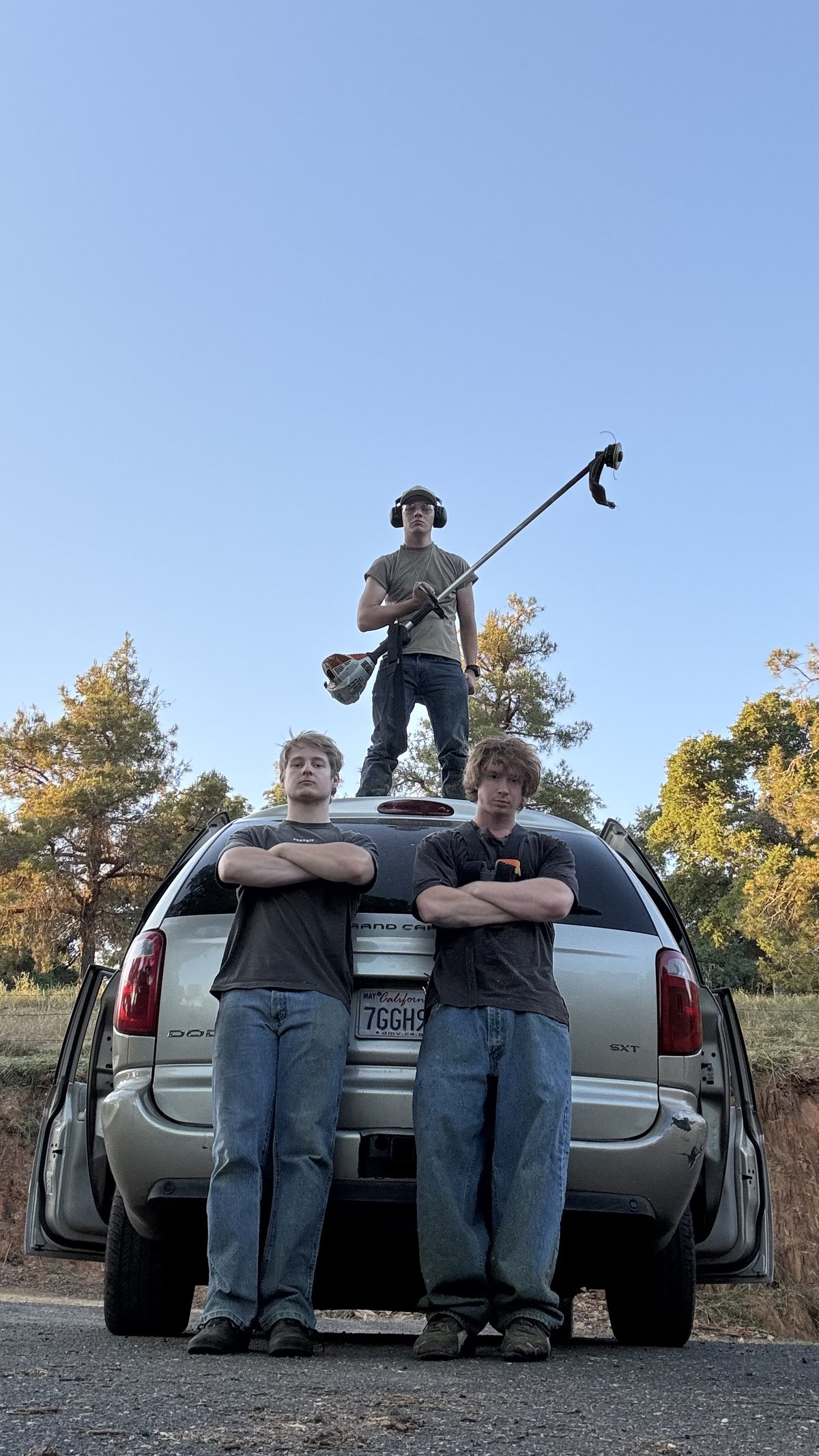 Wacky Weedeating crew posing with weed eaters on truck