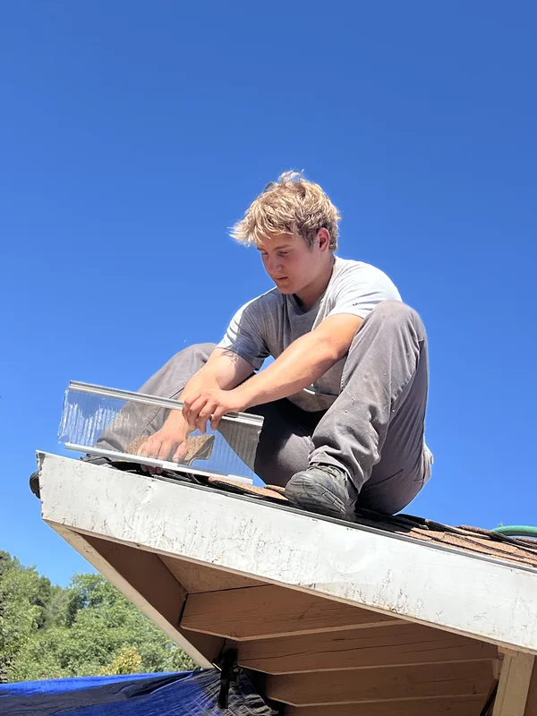 Crew member repairing gutter and fascia on a roof